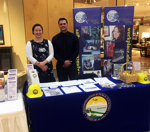 DOPLR HR Consultant Kelley Roberson and DOTPF HR Consultant Trevor Coogan standing at the Workplace Alaska Job Fair booth in Anchorage