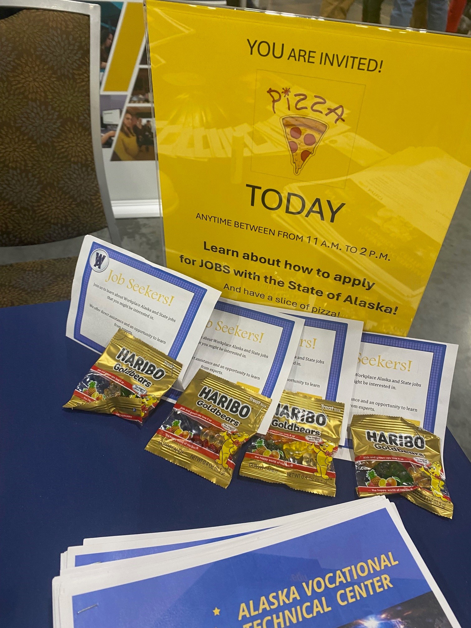 Photo of the DOP welcome table at AFN with a sign, postcards for job seekers, and gummy bears